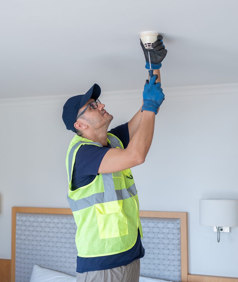 Man in safety vest fixing smoke detector