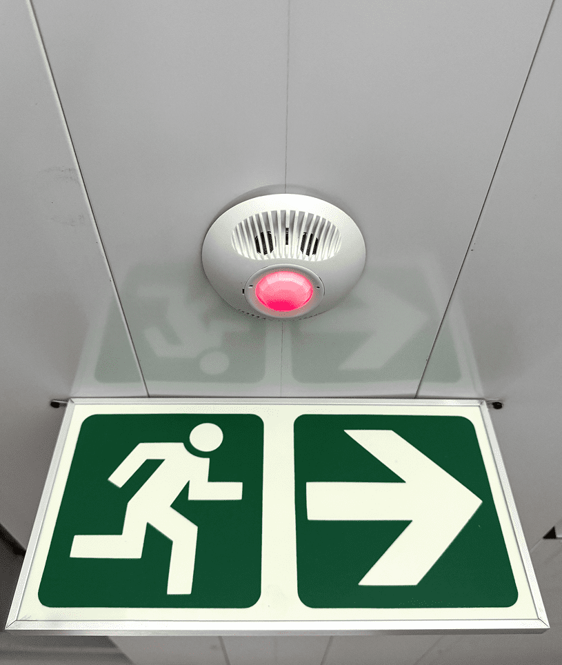 Green exit sign under smoke alarm